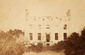 Old sepia photograph of a ruined mansion with empty windows